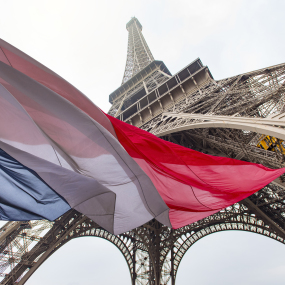 Der Eiffelturm mit der französischen Flagge im Vordergrund.